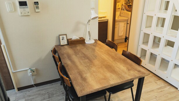 Uma área de jantar com mesa de madeira, cadeiras, luminária e sinal de Wi-Fi fixado na parede.