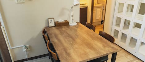 Un comedor con una mesa de madera, sillas, una lámpara y un letrero de Wi-Fi en la pared.