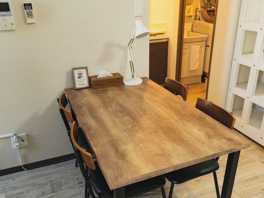 A dining area with a wooden table, chairs, a lamp, and a wall-mounted Wi-Fi sign.