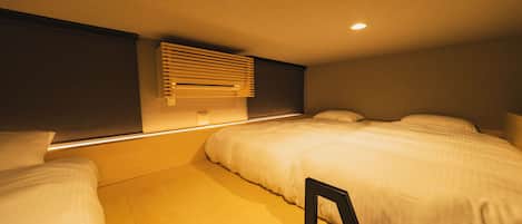 Una habitación de hotel con cama, mesita de noche, aire acondicionado de pared y luz en el techo.