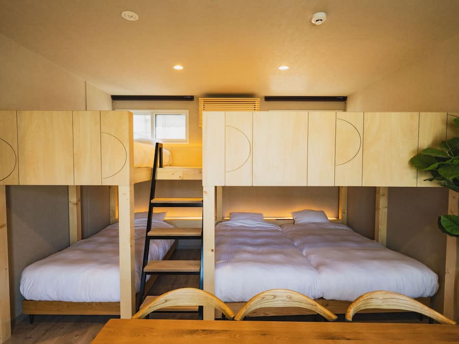 A bunk bed room with a wooden table and a plant.