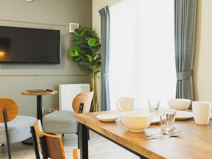 Un coin repas avec une table en bois, des chaises et un téléviseur fixé au mur.