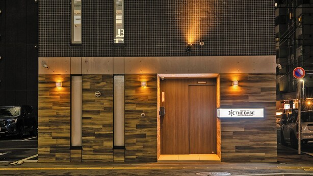 Un edificio moderno con una puerta de madera y un letrero que dice "THE BASE".