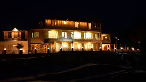 A multi-story hotel with illuminated balconies and a well-lit entrance. - The Alpine Chalet Resort (Dhari)