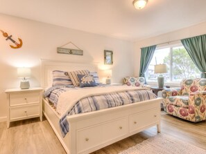 A bedroom with a bed, bedside tables, a chair, and a window with curtains. - W4 - Blue - Whale Inn Pet Friendly Studio (Depoe Bay)