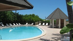 Une piscine avec des chaises longues et un kiosque.