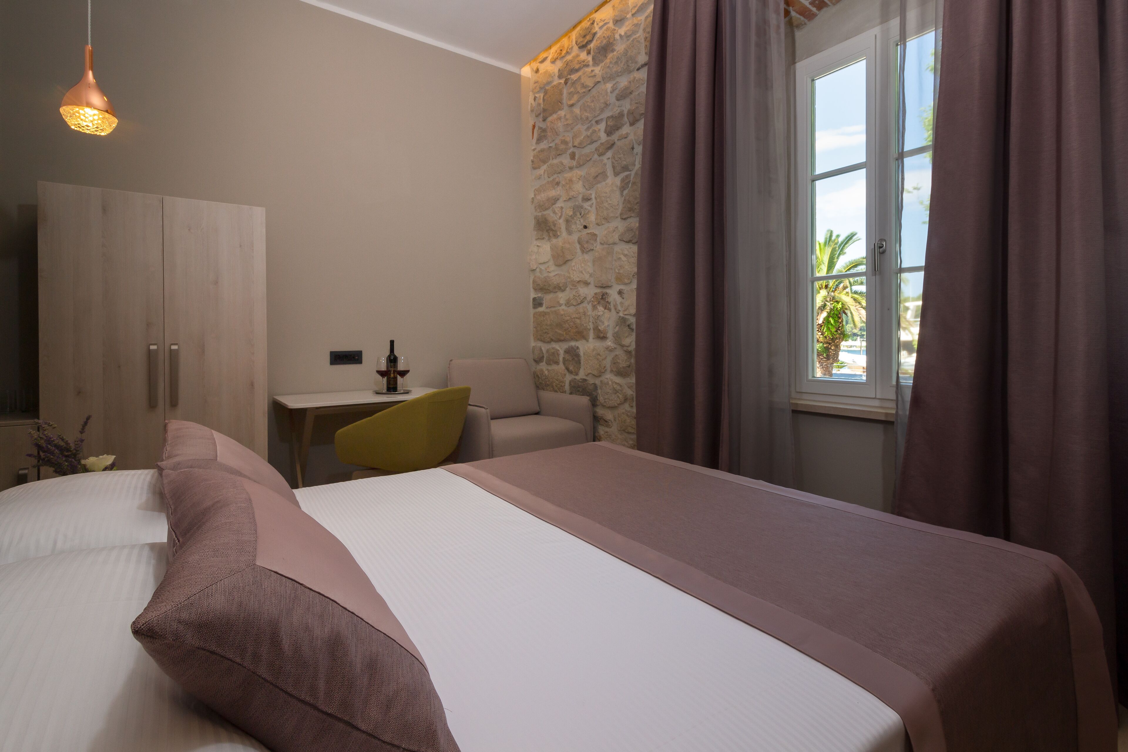 Un dormitorio con una cama, un escritorio, una silla y una pared de piedra.
