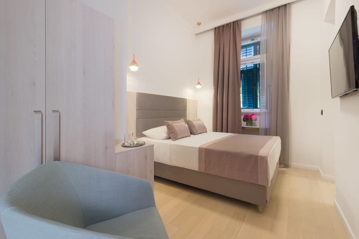 A modern bedroom with a bed, bedside table, and a TV mounted on the wall.