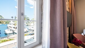 A room with a large window overlooking a marina with boats and a clear sky.