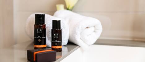 A bathroom with a white towel, two bottles of body lotion, and a small box.