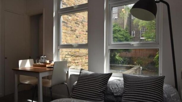 A bedroom with a large window, a desk, and a chair. - Cozy Apartment in Camden Town (London)