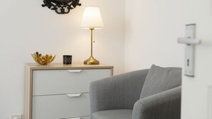 A modern room with a grey sofa, a bedside table with a lamp, a decorative bowl, and a mirror. - Cozy Apartment in Camden Town (London)