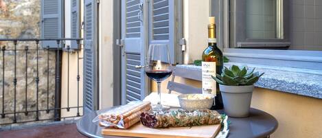 A table with a bottle of wine, a glass, and food items on a balcony.