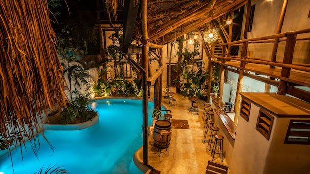 A pool area with a thatched roof, wooden furniture, and tropical plants. - Hotel Boutique TerraNova (Tulum)