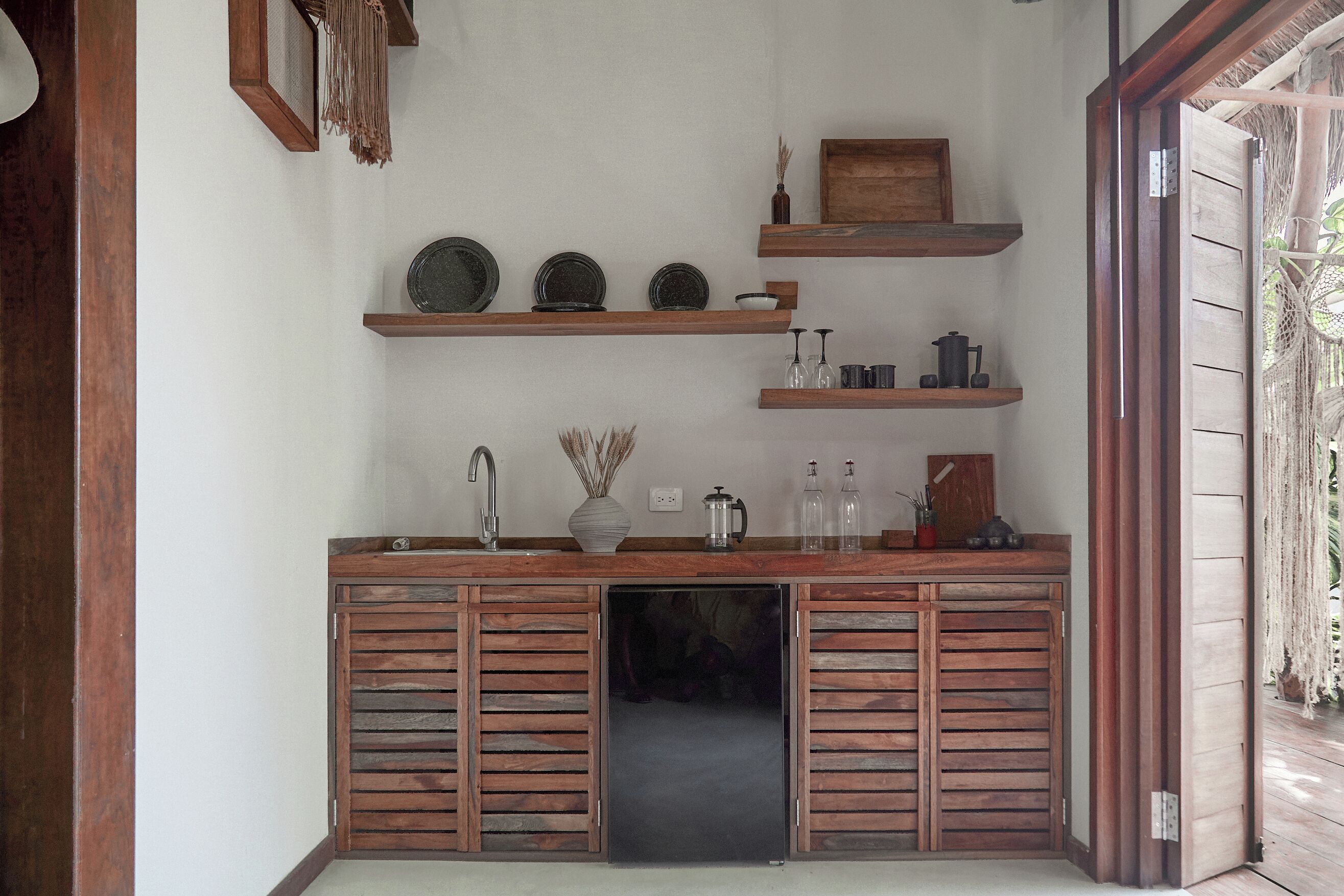 A kitchen with wooden cabinets, a sink, and shelves with kitchenware.
