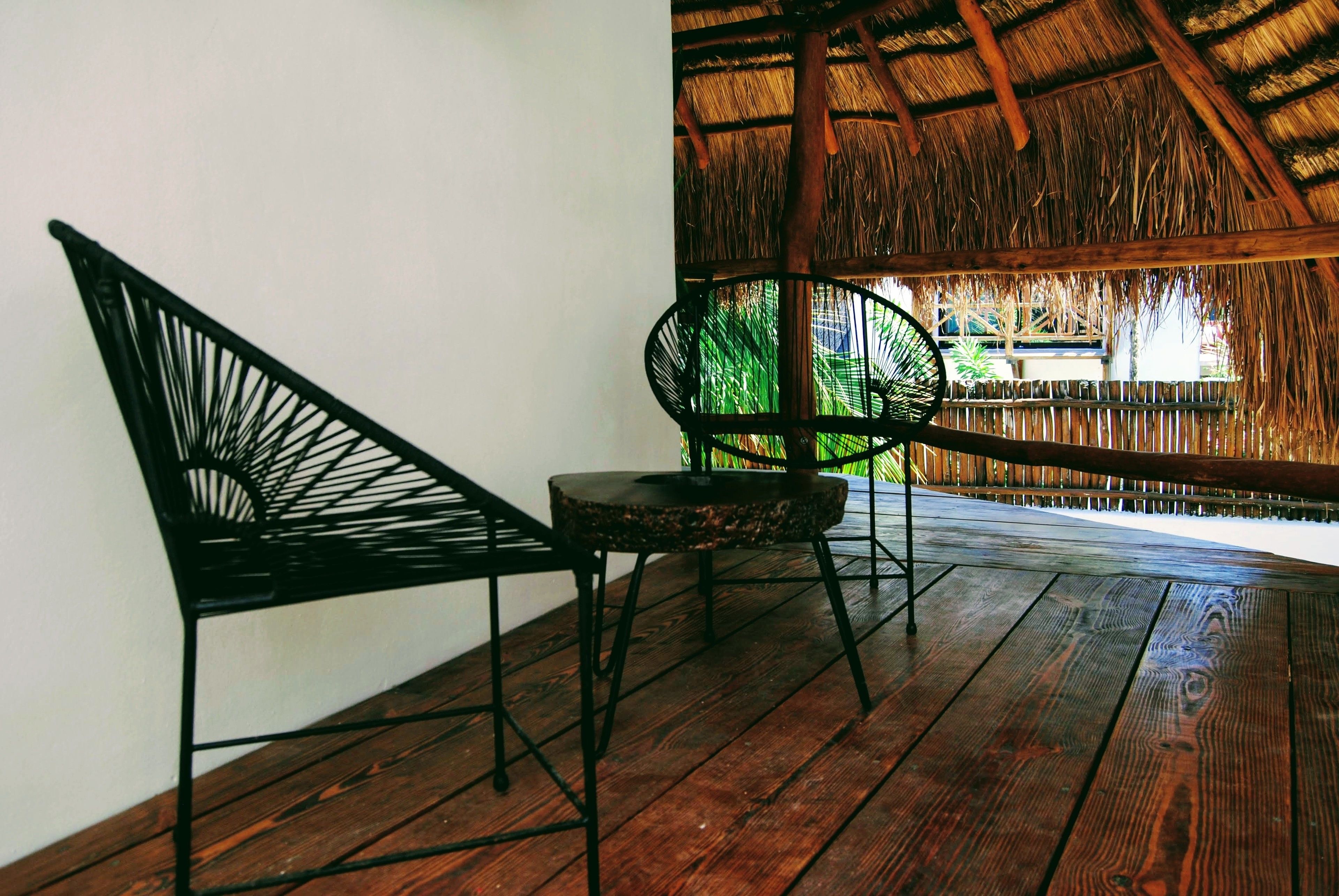 Una terraza de madera con dos sillas de metal negro y una pequeña mesa redonda.