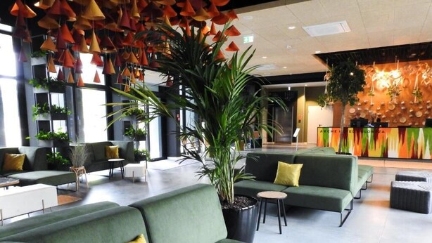 A modern lobby with green sofas, yellow cushions, and a large potted plant. - Arche Hotel Poloneza (Warsaw)
