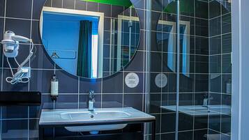 Un baño moderno con un espejo grande, un lavabo y una zona de ducha.