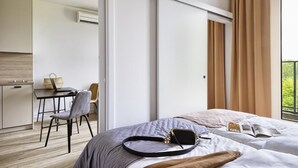 A hotel room with a bed, a desk with a chair, a small table, and a window with curtains. - Arche Hotel Poloneza (Warsaw)
