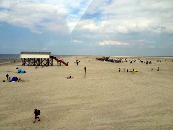 A beach with a pier, tents, and a lifeguard tower.
