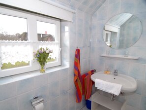 A bathroom with a window, a sink, a mirror, and a toilet.