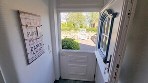 A door with a sign on the wall, a window with curtains, and a view of the outside.