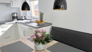 Eine moderne Küche mit Essbereich, einer Kaffeemaschine, einer Obstschale und einem Blumenstrauß.