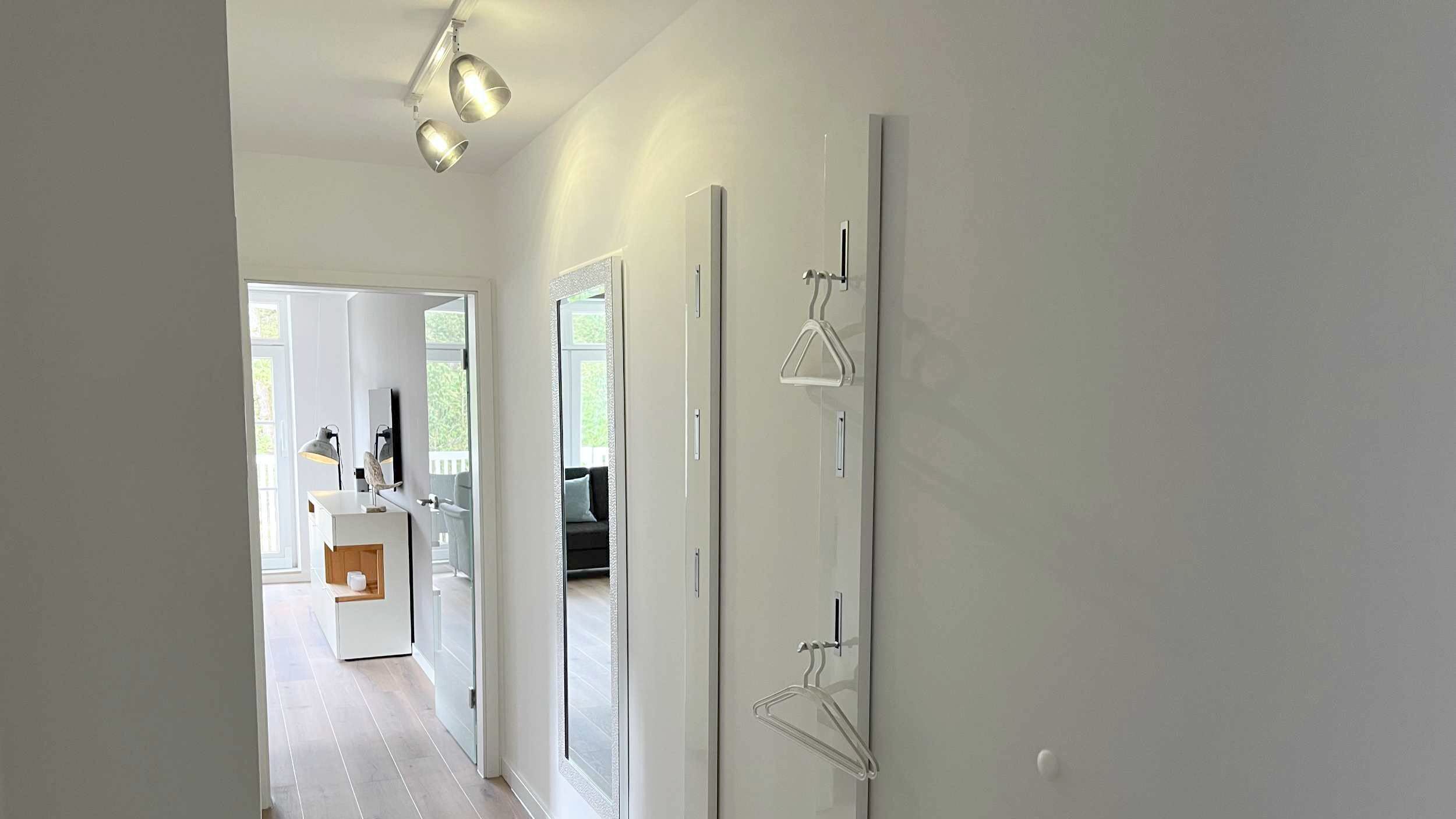 A hallway with a modern interior, a door with a towel rack, and a view into another room.