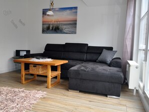 A modern living room with a sectional sofa, a wooden coffee table, and a painting of a beach scene.