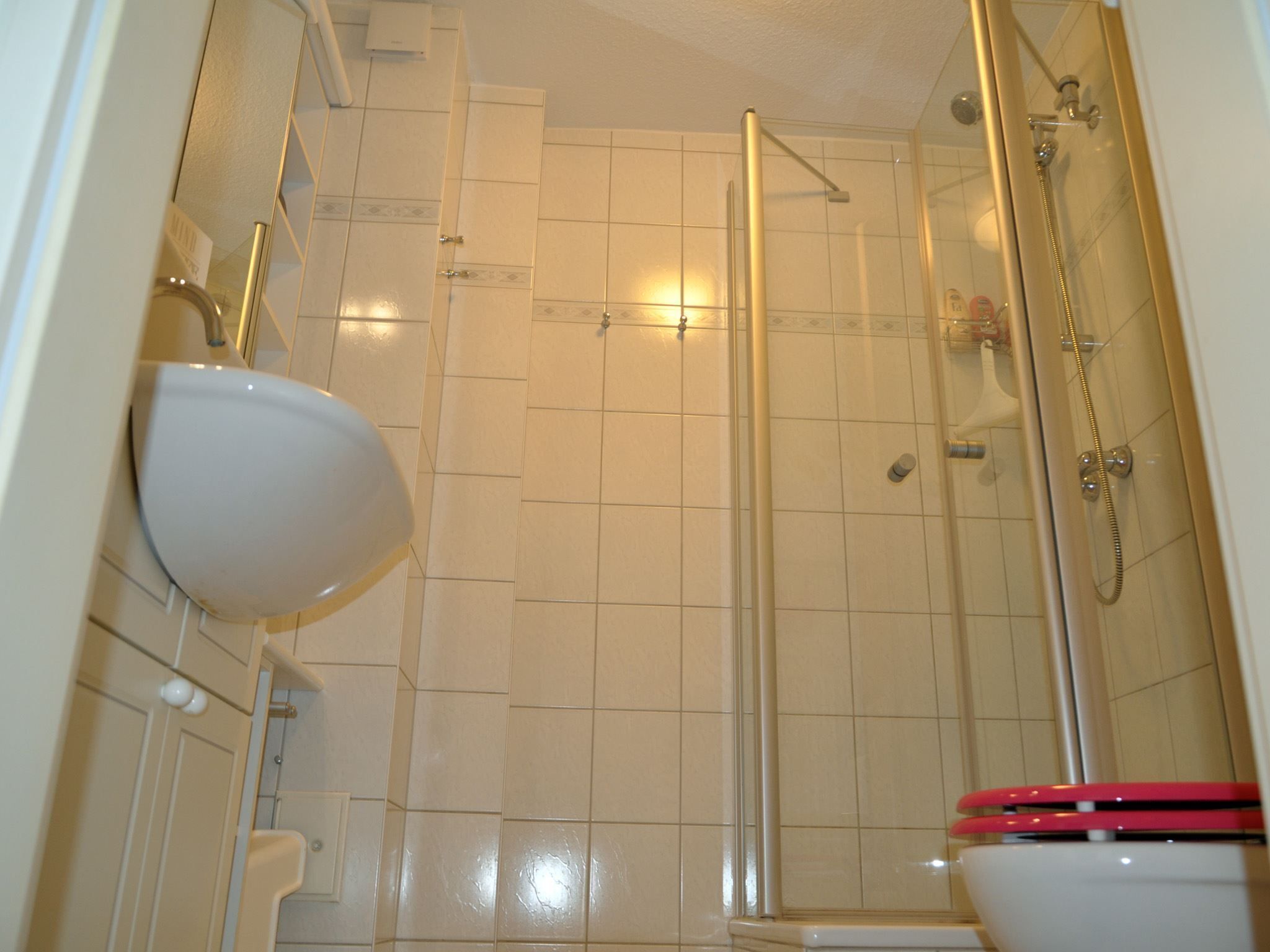 A bathroom with a toilet, sink, and glass-enclosed shower stall.