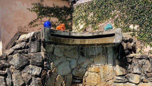 A swimming pool with a stone wall and a person swimming. - Taverna do Paraíso (Paulista)