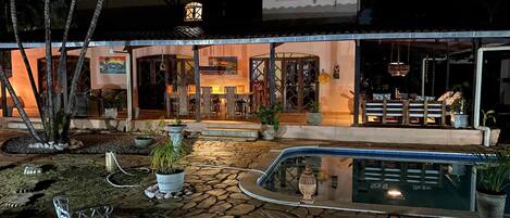 A hotel with a pool, outdoor seating, and a well-lit entrance.