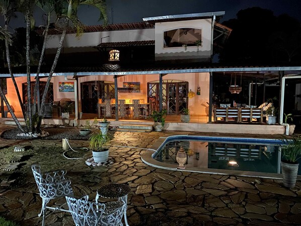 Un hotel con piscina, asientos exteriores e ingreso bien iluminado.