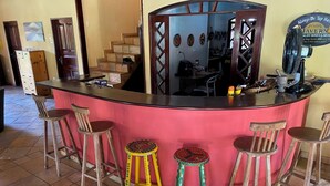 A bar area with a counter, stools, and a mirror. - Taverna do Paraíso (Paulista)