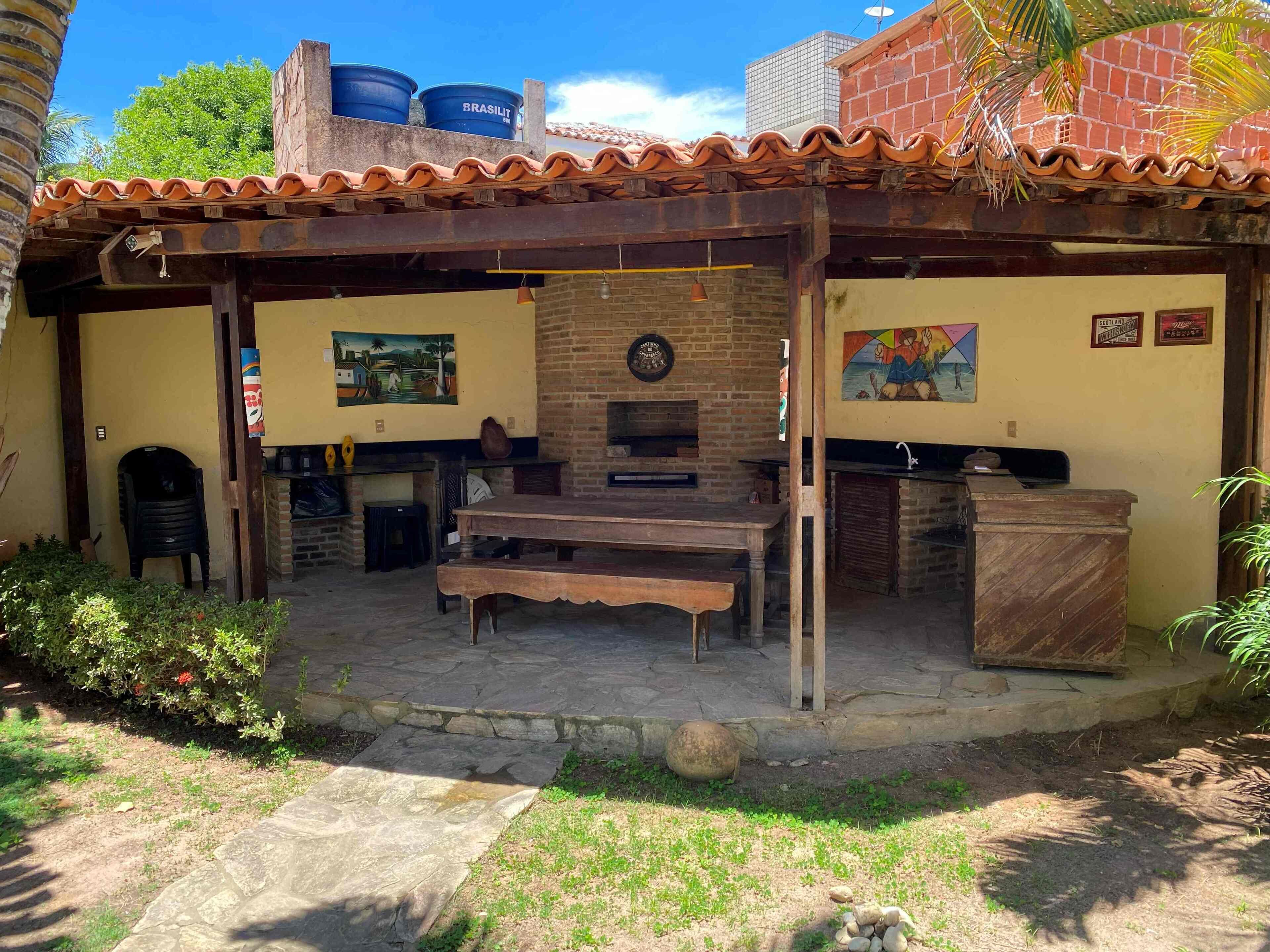 Patio esterno con camino in mattoni, tavolo e sedie in legno.