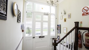 A staircase with a white handrail and a dark wooden balustrade leading to a door with a white frame. - Primrose Guest House (London)