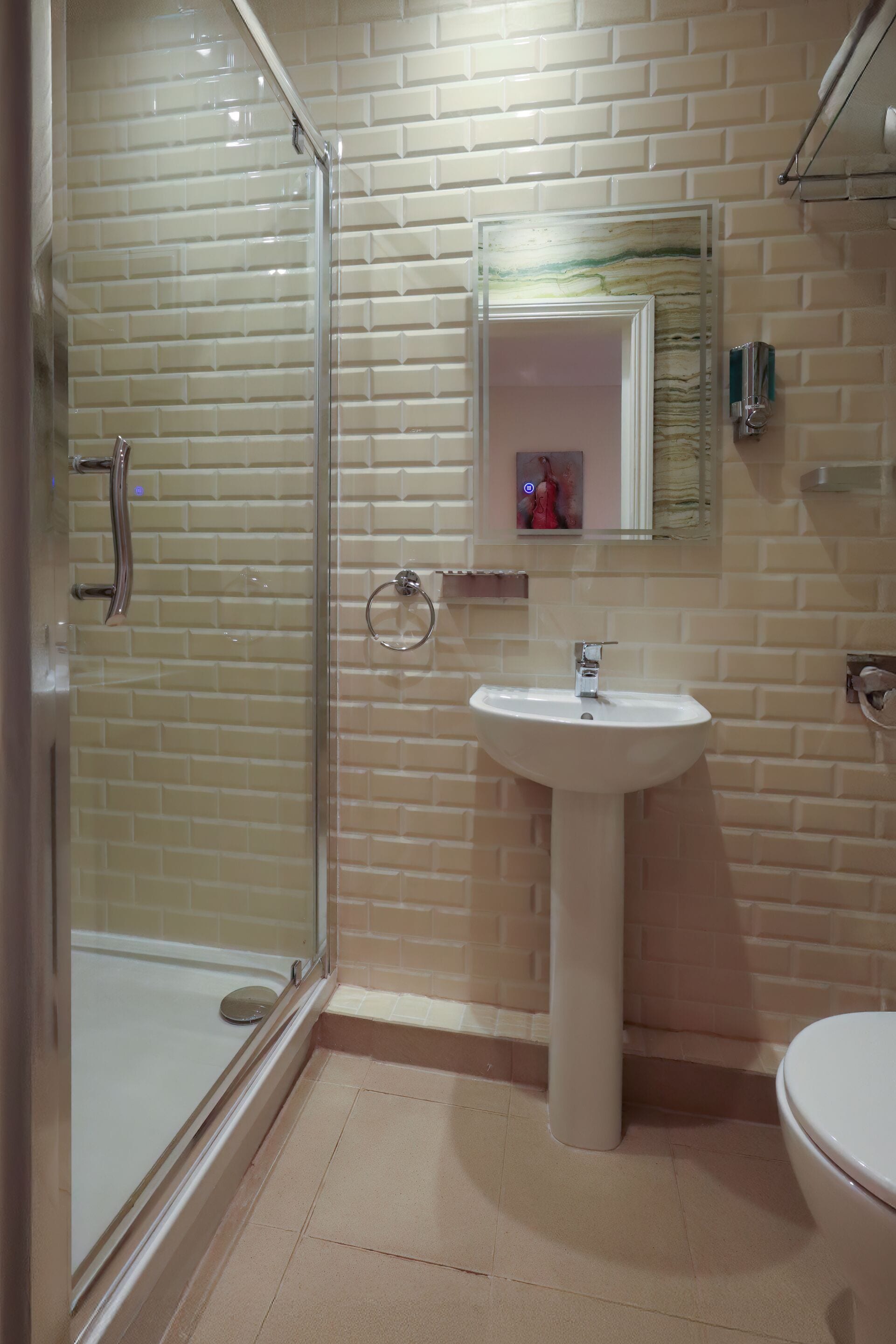 Un baño con cabina de ducha de vidrio, lavamanos pedestal y retrete.