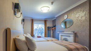 A hotel room with two beds, a mirror, a clock, and a fireplace. - Primrose Guest House (London)