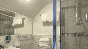 Un baño moderno con cabina de ducha de vidrio, inodoro blanco y lavamanos con espejo sobre él.