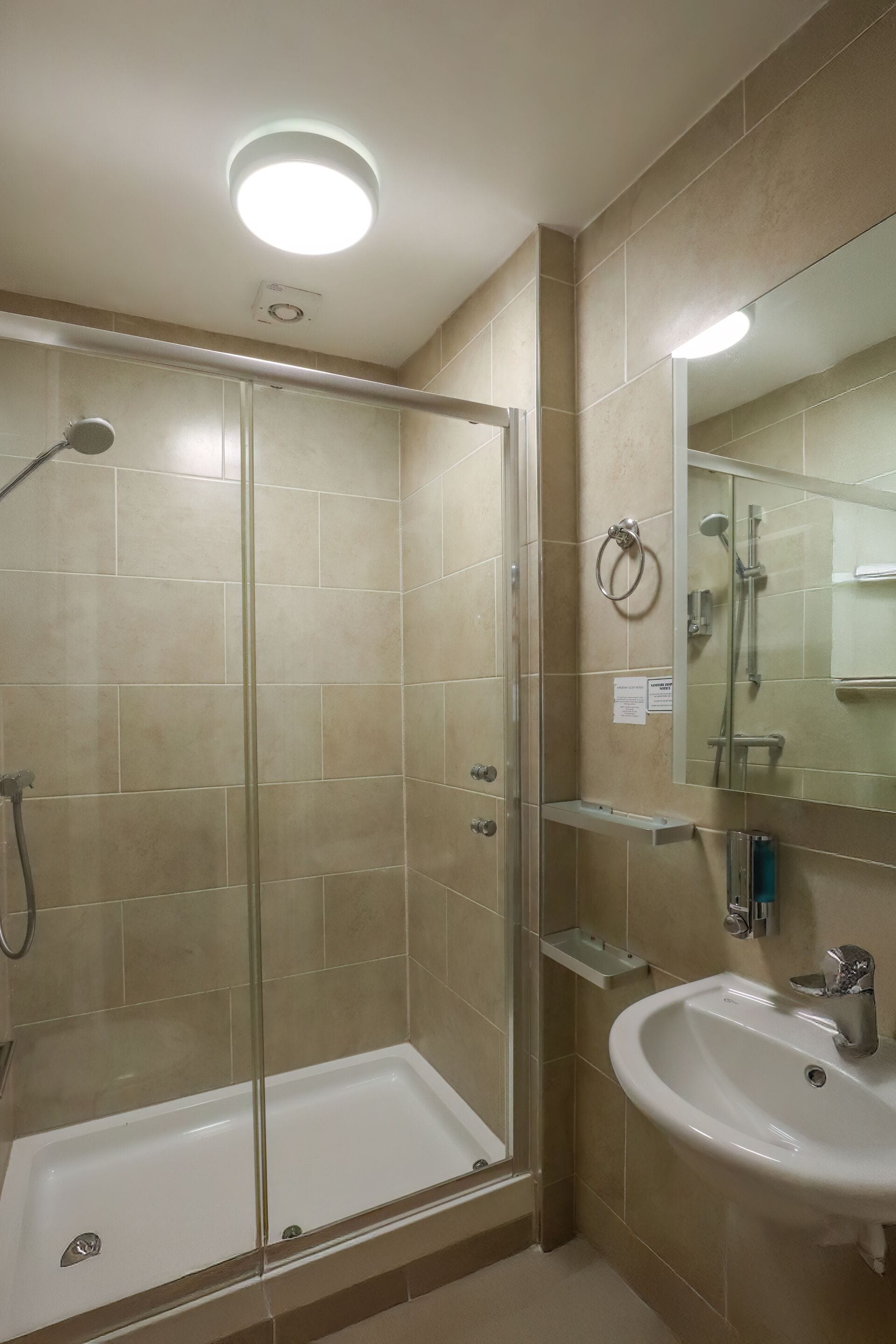 A bathroom with a glass-enclosed shower, a sink, and a mirror.