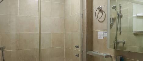 A bathroom with a glass-enclosed shower, a sink, and a mirror.