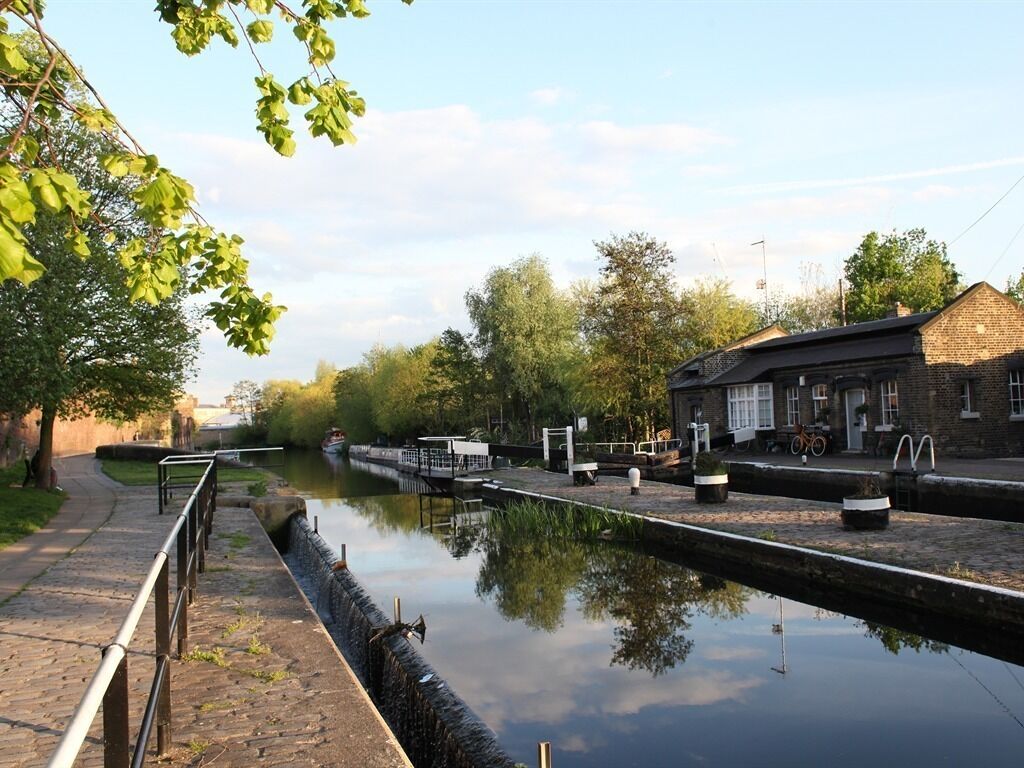 A canal with a lock system, a pathway, and a building with a brick facade.