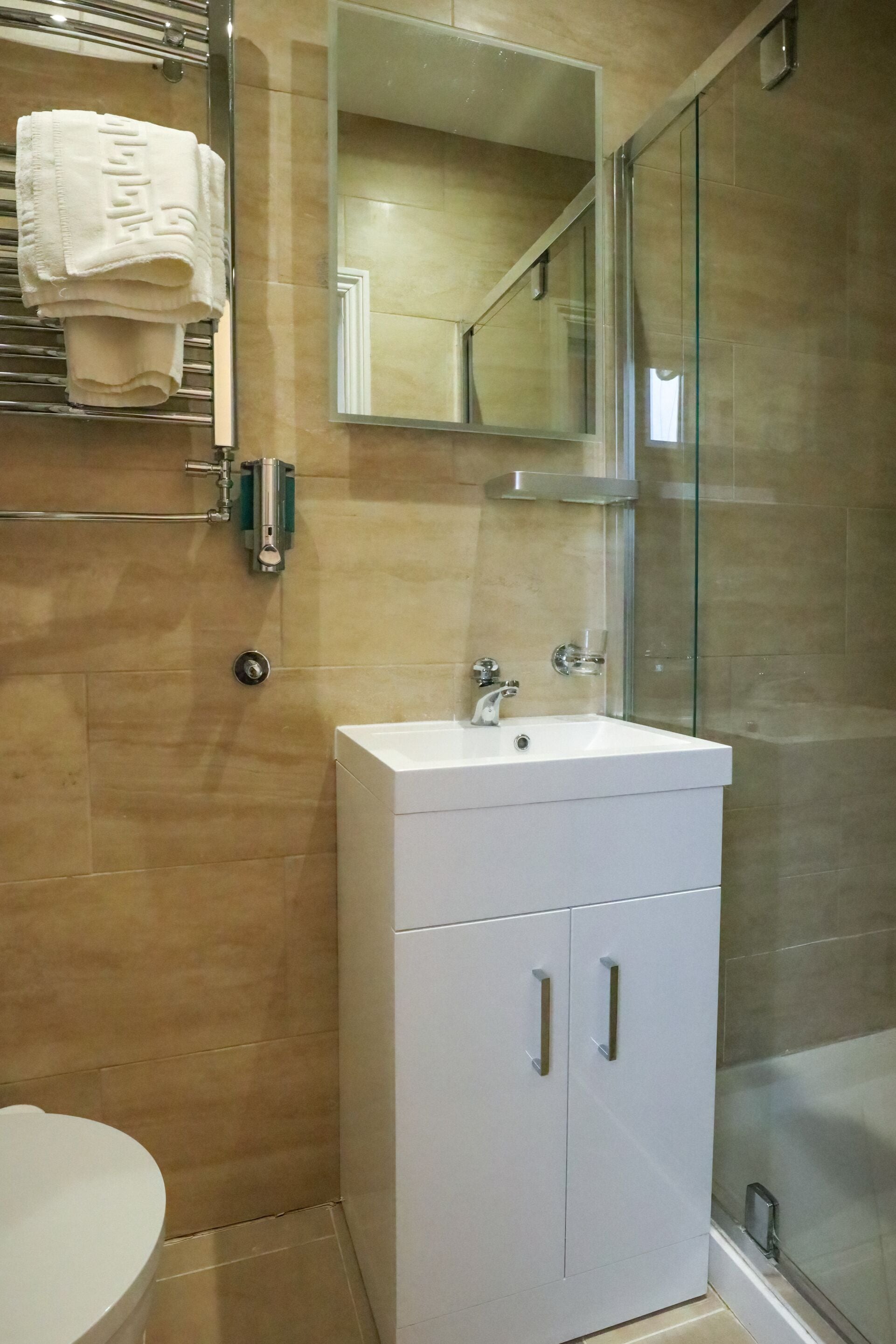 A bathroom with a white sink, a mirror, and a glass shower enclosure.