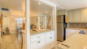 Una cocina moderna con armarios blancos, un refrigerador de acero inoxidable y una encimera de granito.