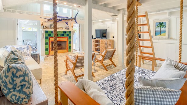 Amplia sala de estar con chimenea, televisor y vistas al exterior.