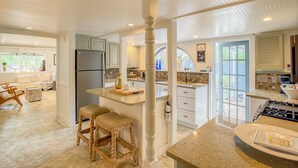 Una cocina amplia con una isla grande, armarios blancos y vistas al área de comedor.