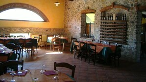 A restaurant with stone walls, wooden beams, and tables set for dining. - Amarcord (Spezzano Albanese)