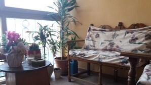 A room with a wooden sofa, a small round table with a vase and candles, and several potted plants. - La Maison del Corso B&B (Pisa)