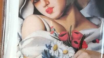 Un tableau encadré représentant une femme portant un chapeau blanc et tenant un bouquet de fleurs.