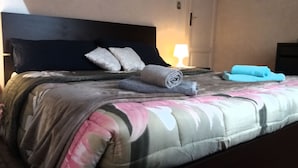 A neatly made bed with a floral-patterned bedspread, pillows, and rolled towels. - La Maison del Corso B&B (Pisa)